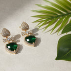 SVORA gold-tone earrings with pavé heart studs, bow connectors, and emerald crystal heart drops.
