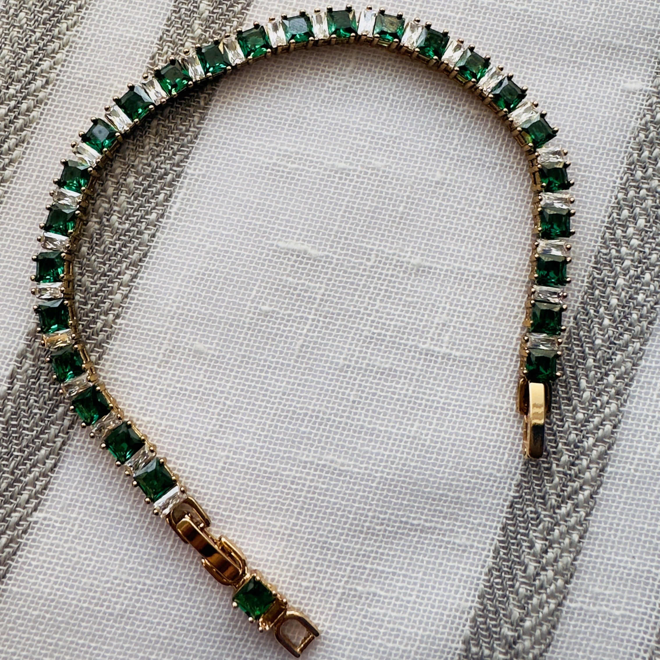 SVORA Emerald Tennis Adjustable Bracelet with alternating emerald green and clear square-cut stones, 18k gold-plated stainless steel.