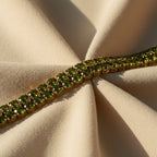 SVORA gold-plated tennis bracelet with double row of oval emerald green CZ stones. Fold-over clasp.