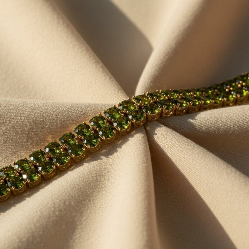 SVORA gold-plated tennis bracelet with double row of oval emerald green CZ stones. Fold-over clasp.