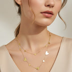 SVORA gold-tone stainless steel drape necklace with multiple polished heart charms and delicate chainwork.
