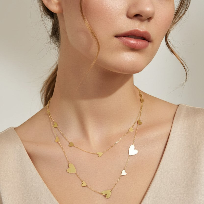 SVORA gold-tone stainless steel drape necklace with multiple polished heart charms and delicate chainwork.