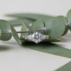 SVORA Ethereal Amour Solitaire Ring with round-cut center stone and heart-cut accent stones on a silver band.