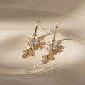 SVORA Flora Stones Dangler Earrings with gold-tone stainless steel, cubic zirconia flowers and leaf details.