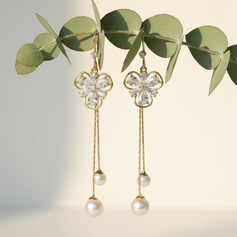 SVORA gold tone dangle earrings with cubic zirconia flower studs and pearl drops on chains.