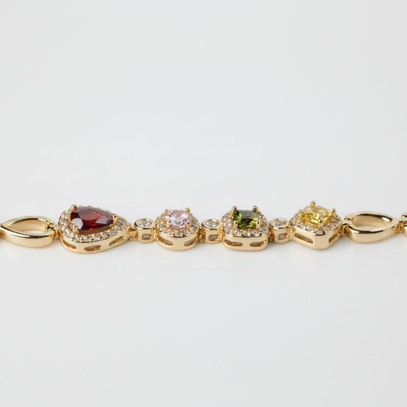 SVORA geometric multicolor bracelet with garnet, pink, peridot, and citrine stones in CZ halos, linked by gold chain. 18K gold plated.