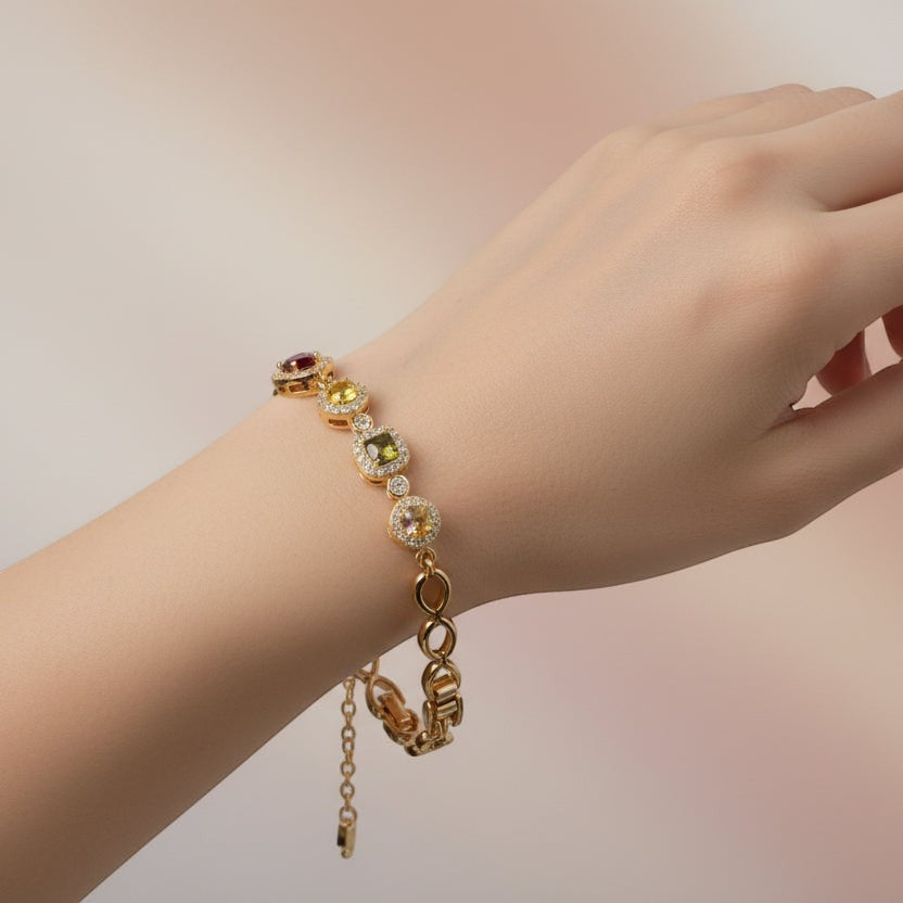 SVORA geometric multicolor bracelet with citrine yellow, peridot, pink, and garnet stones in CZ halos, linked by gold chain. Adjustable clasp.