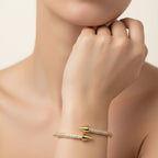 SVORA gold plated stainless steel bypass bracelet with two pavé arrowhead ends, adorned with cubic zirconia.
