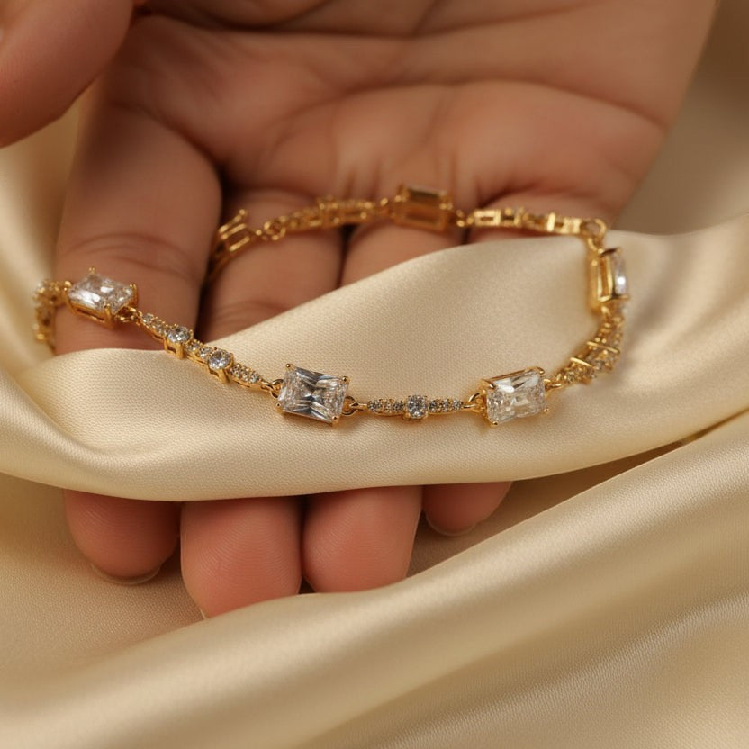 SVORA gold plated stainless steel tennis bracelet with emerald-cut CZ baguettes and round stones.