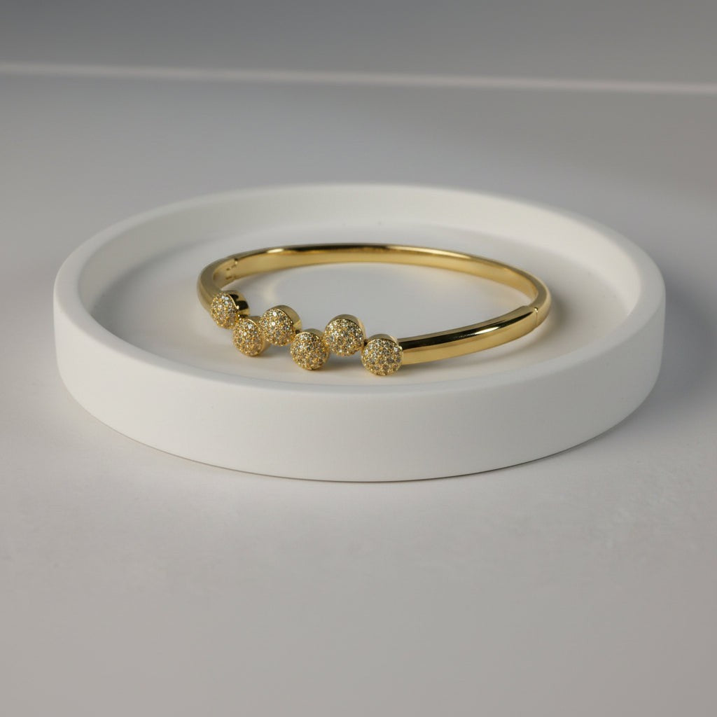 SVORA gold plated stainless steel bangle bracelet with six pavé cubic zirconia domes in a row.