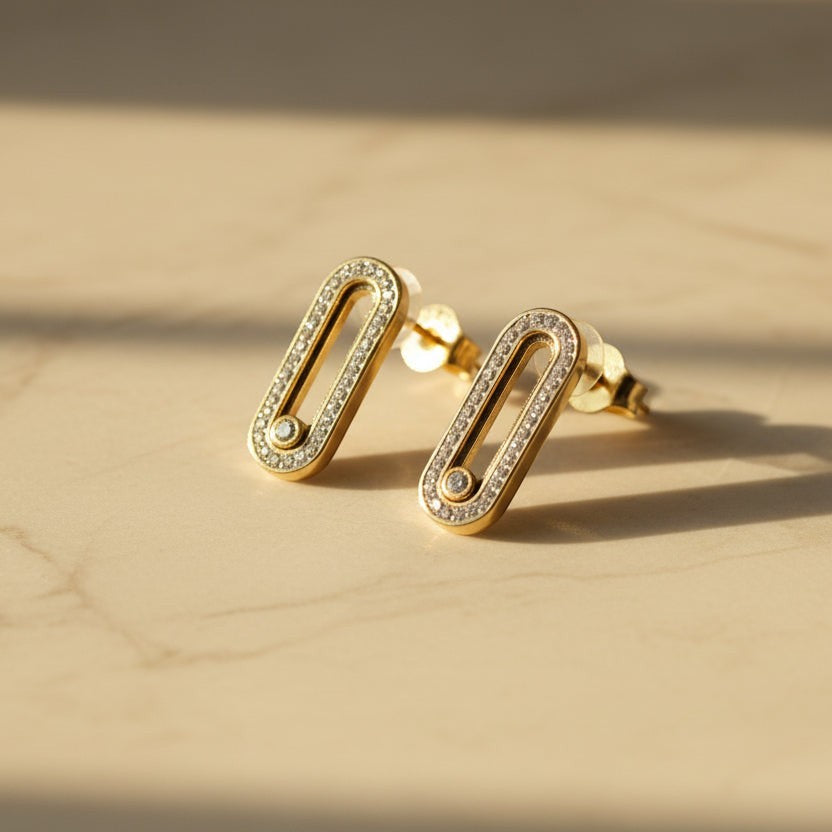 SVORA gold tone stainless steel dangle earrings with pavé cubic zirconia bar and moving stone detail.