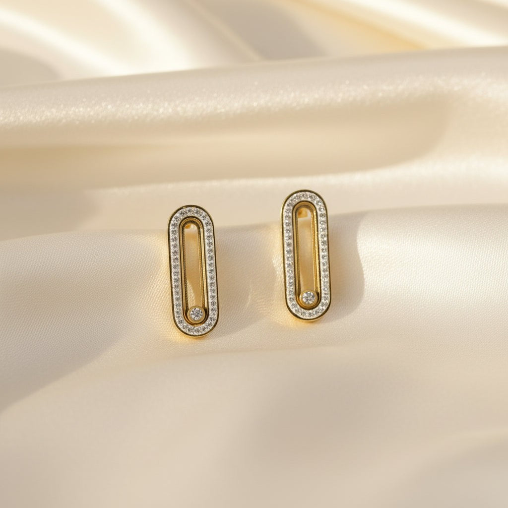 SVORA gold tone stainless steel dangler earrings with pavé cubic zirconia bar and moving center stone.
