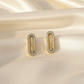 SVORA gold tone stainless steel dangler earrings with pavé cubic zirconia bar and moving center stone.