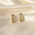 SVORA gold tone stainless steel dangler earrings with pavé cubic zirconia bar and moving center stone.