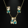 SVORA gold-tone necklace and earrings set with blue, lavender, and cream stones in a caged design.
