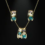 SVORA gold-tone necklace and earrings set with blue, lavender, and cream stones in a caged design.