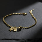 SVORA gold-plated stainless steel bracelet with bow and ball charms on a bead chain. Adjustable lobster clasp.