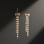 SVORA gold tone dangle earrings with pavé bow top and cascading freshwater pearls and chains.