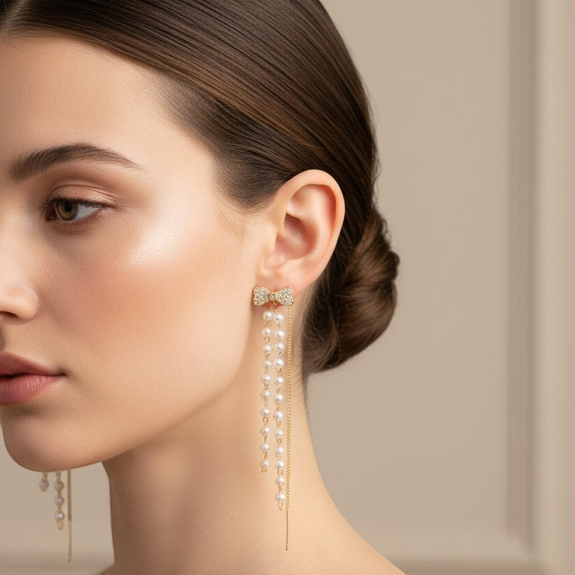 SVORA gold-tone stainless steel bow pearl dangler earrings with cubic zirconia accents.