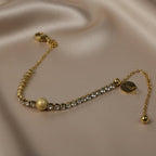 SVORA gold plated stainless steel bracelet with CZ stones and a central textured gold ball. Adjustable.