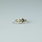 SVORA gold tone stainless steel ring with channel-set baguette cubic zirconia stones in a buckle design.