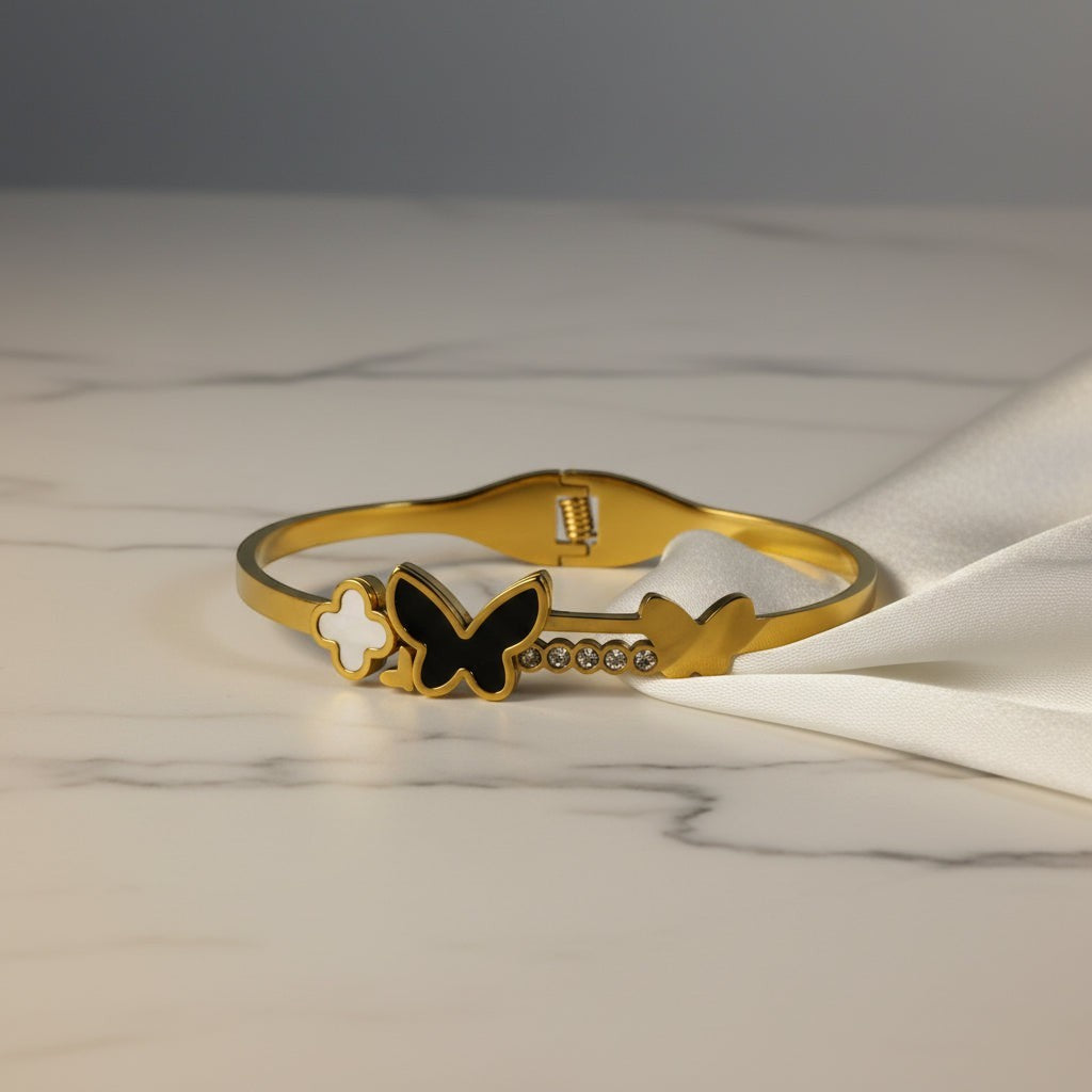 SVORA gold-plated stainless steel bracelet with black onyx butterfly, white pearl clover, and crystal accents.
