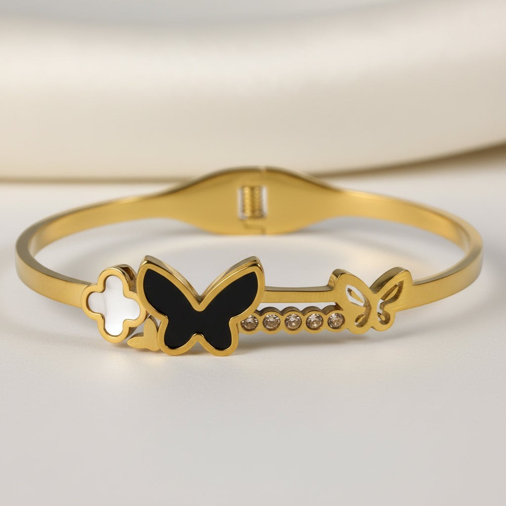 SVORA gold-plated stainless steel bracelet with black onyx butterfly, white clover, and small gold butterfly with cubic zirconia accents.