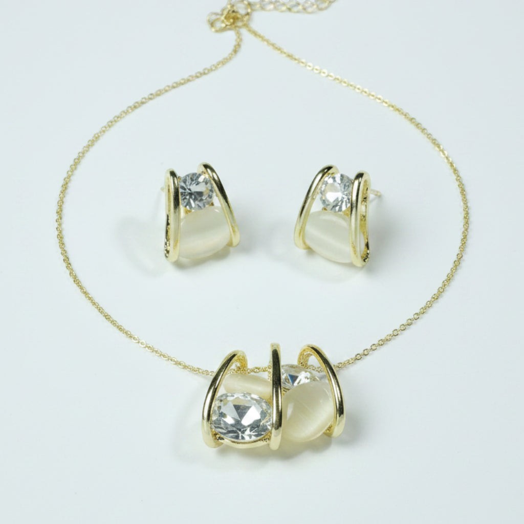 SVORA gold tone necklace and earrings set with clear cubic zirconia and cream cabochon stones in a caged design.