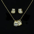 SVORA gold tone necklace and earrings set with clear cubic zirconia and cream cabochon stones in a caged design.