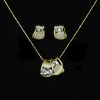 SVORA gold tone necklace and earrings set with clear cubic zirconia and cream cabochon stones in a caged design.