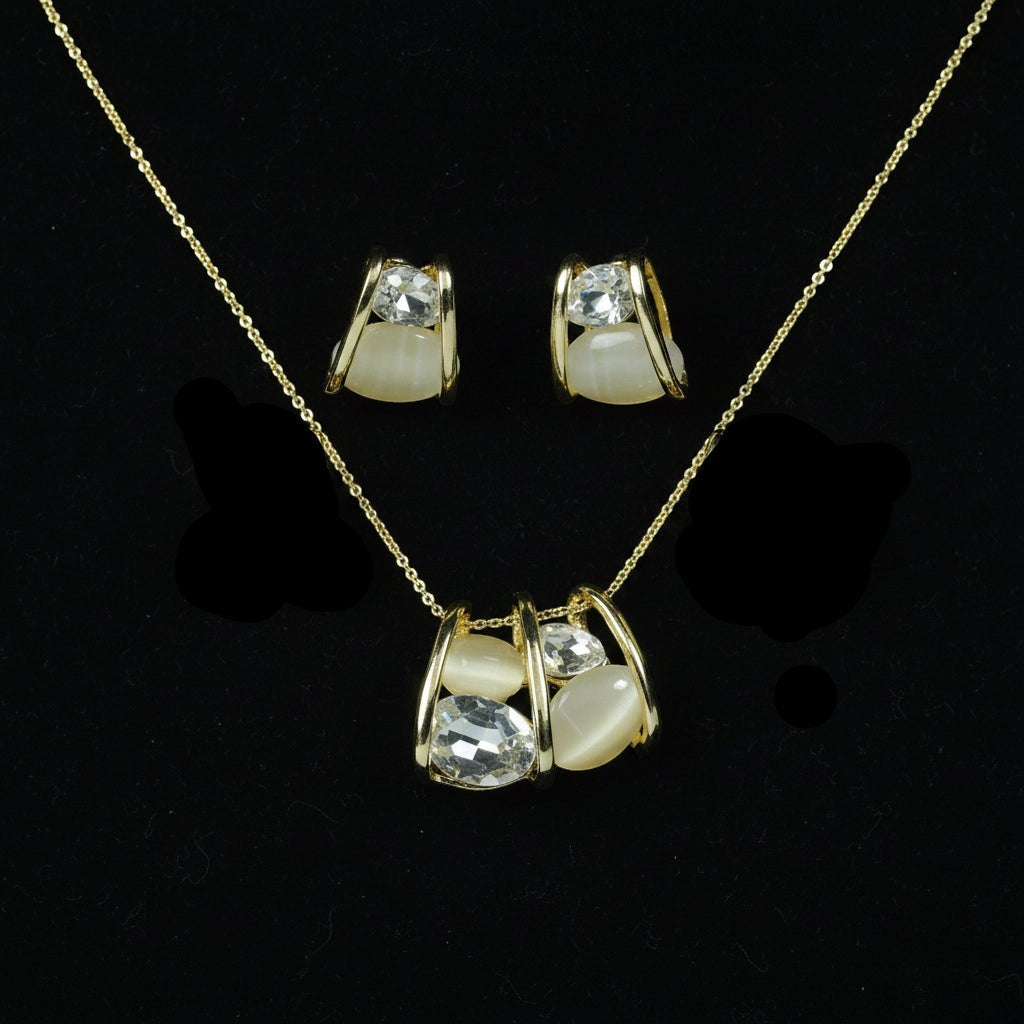 SVORA gold tone necklace and earrings set with clear cubic zirconia and cream cabochon stones in a caged design.