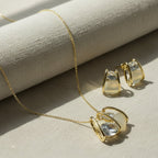 SVORA gold tone necklace and earrings set with clear cubic zirconia and cream cabochon stones in a caged design.