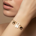 SVORA gold plated stainless steel bracelet with a clover and two heart charms. Adjustable with lobster clasp.