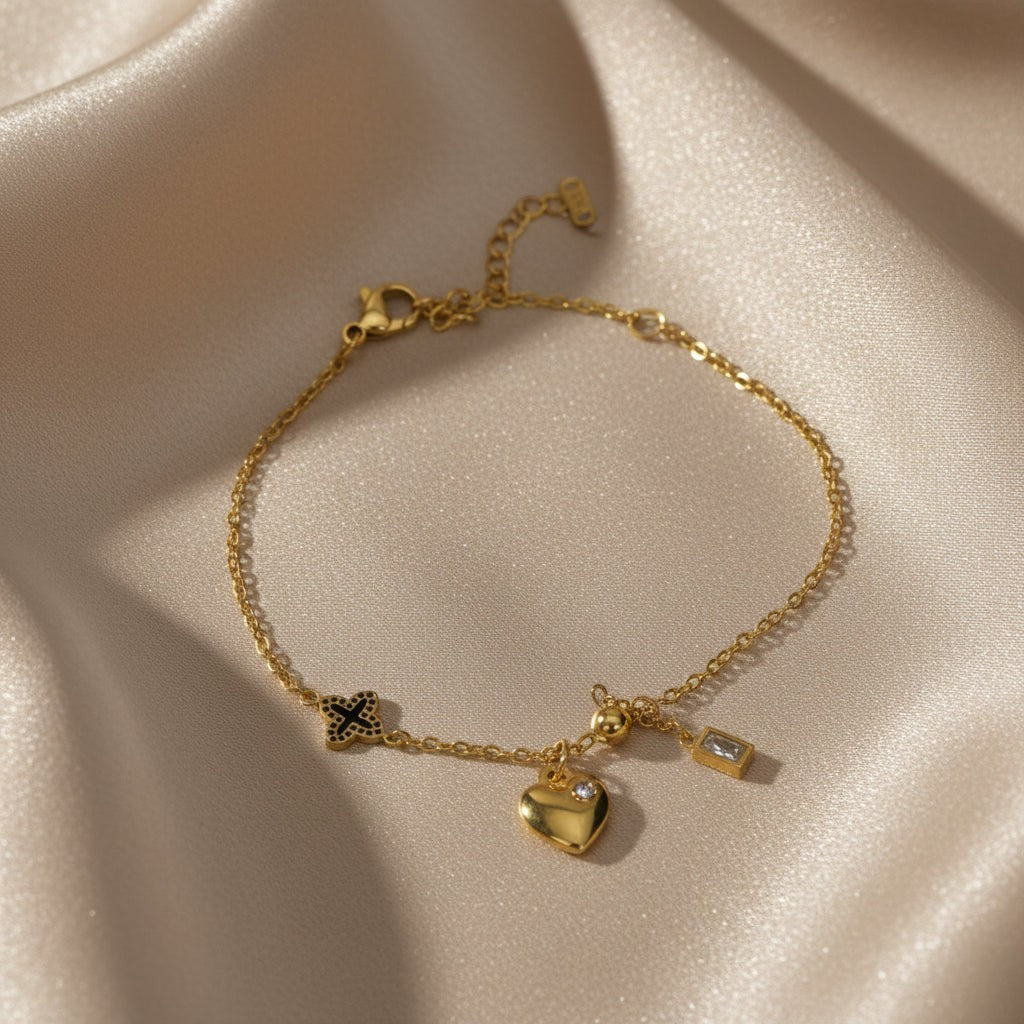 SVORA gold plated stainless steel bracelet with heart, clover, ball, and rectangle charms. Adjustable.
