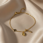 SVORA gold plated stainless steel bracelet with heart, clover, ball, and rectangle charms. Adjustable.