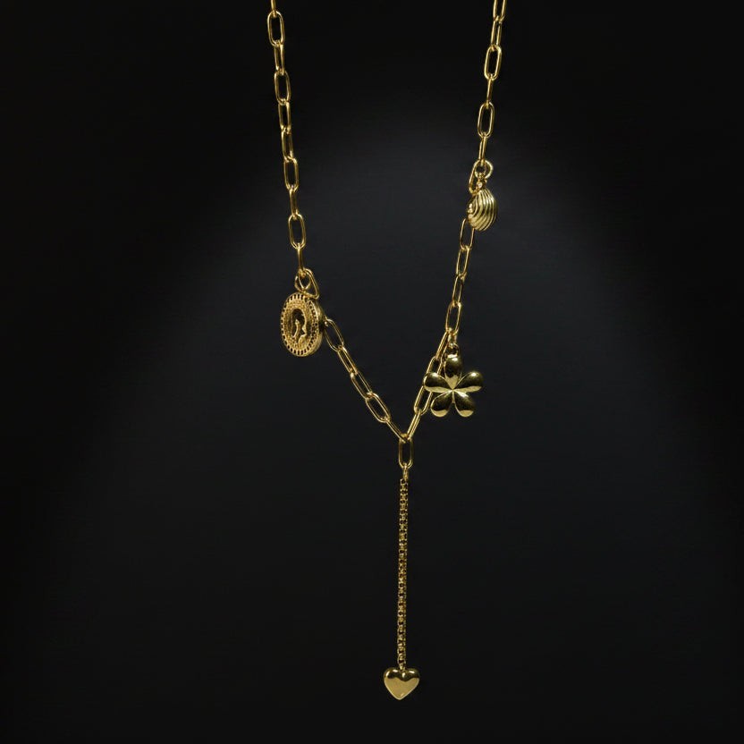 SVORA gold paperclip chain necklace with daisy, shell, coin, and heart charms. 18K gold plated stainless steel.