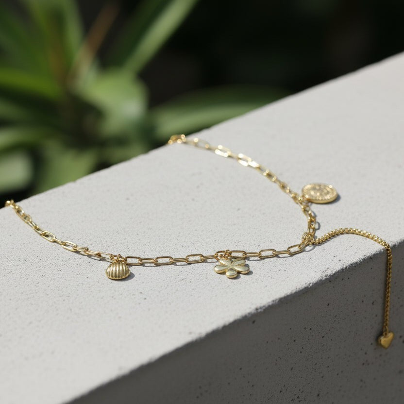 SVORA gold paperclip chain necklace with daisy, shell, coin, and heart charms. 18K gold plated stainless steel.