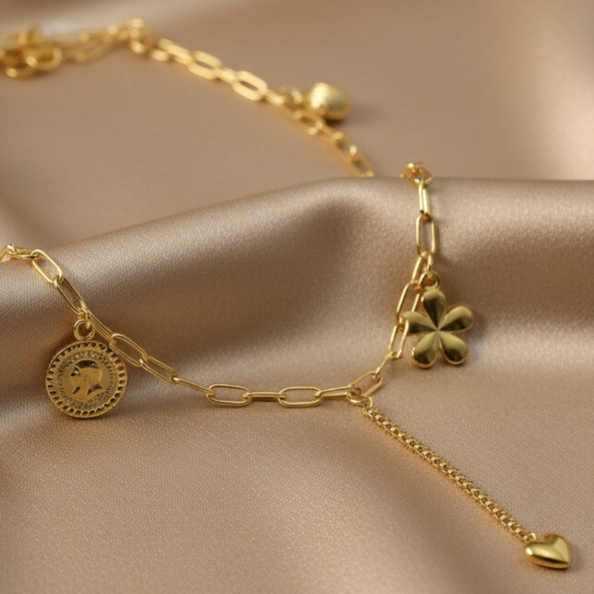 SVORA gold paperclip chain necklace with daisy, shell, coin, and heart charms. 18K gold plated stainless steel.