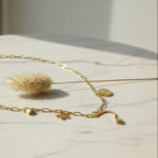 SVORA gold paperclip chain necklace with daisy, shell, coin, and heart charms. 18K gold plated stainless steel.