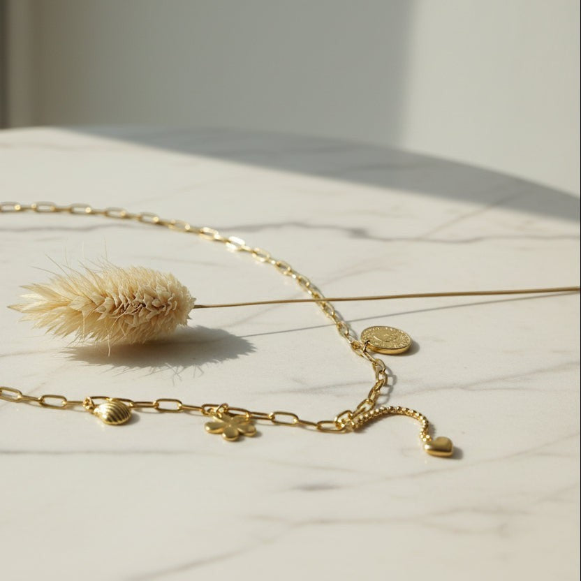SVORA gold paperclip chain necklace with daisy, shell, coin, and heart charms. 18K gold plated stainless steel.