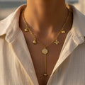 SVORA gold paperclip chain necklace with daisy, shell, coin, and heart charms. 18K gold plated stainless steel.