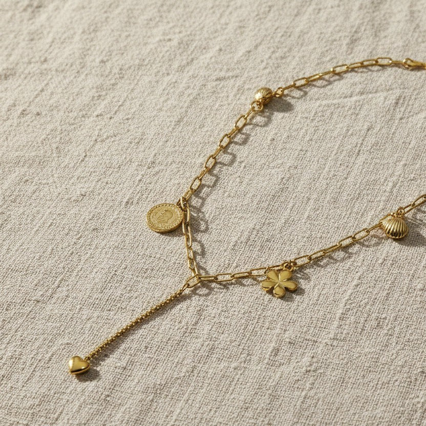 SVORA gold paperclip chain necklace with daisy, shell, coin, and heart charms. 18K gold plated stainless steel.