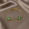 SVORA gold double chain bracelet with two green clover charms, each with a small CZ center. Adjustable.