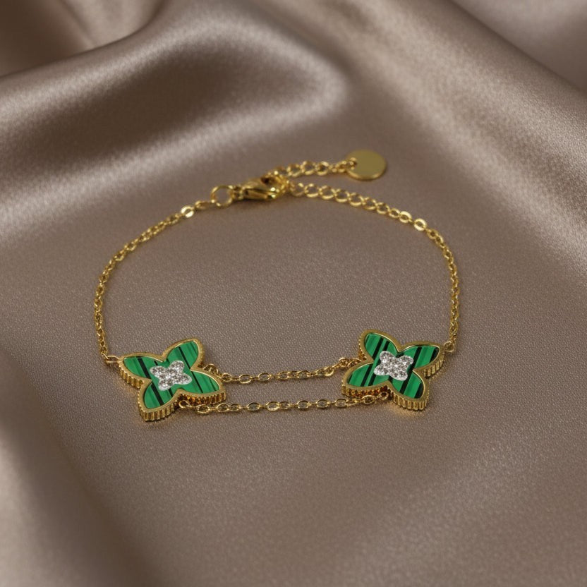 SVORA gold double chain bracelet with two green clover charms, each with a small CZ center. Adjustable.