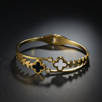 SVORA gold-plated stainless steel bracelet with black onyx and white mother-of-pearl clover charms and leaf details.