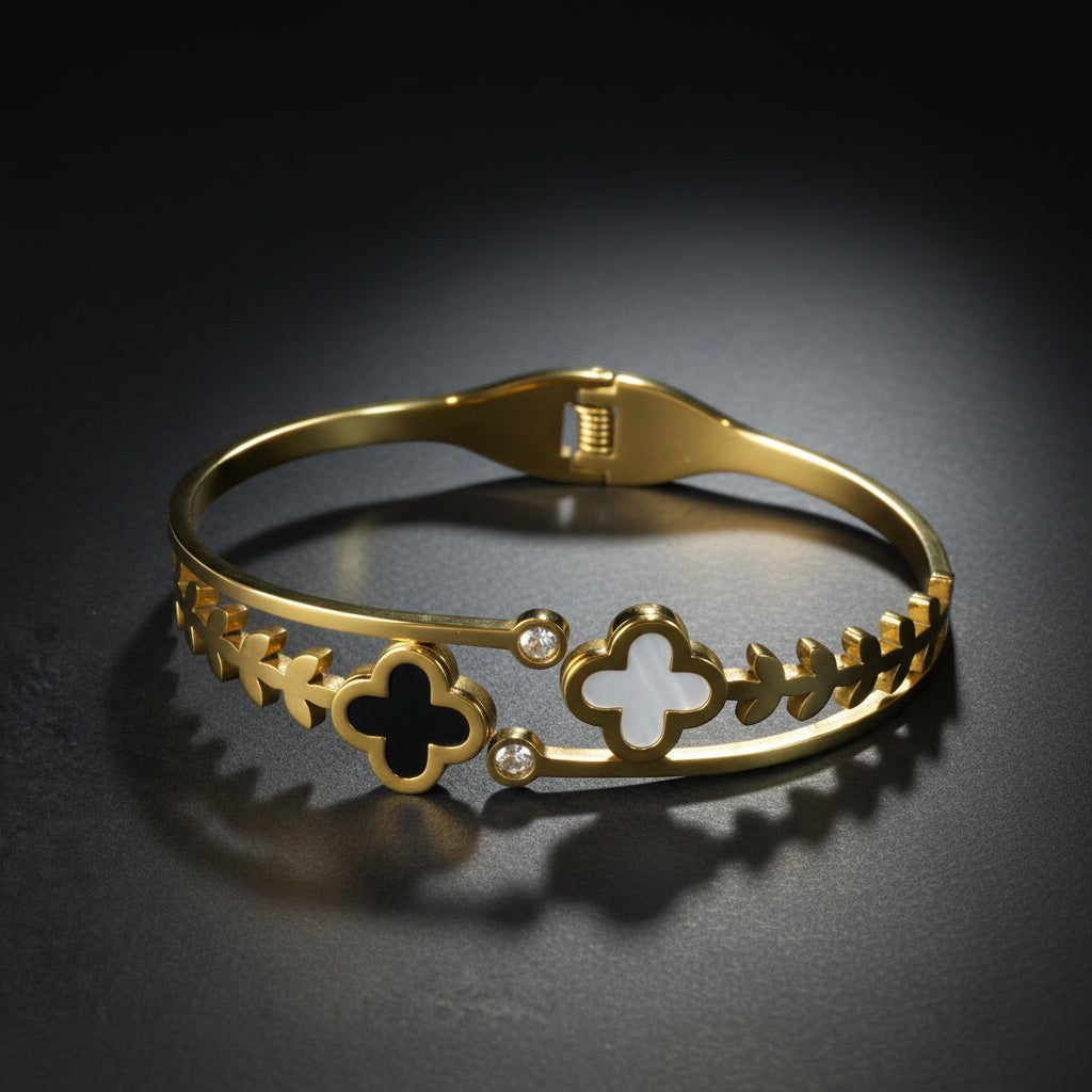 SVORA gold-plated stainless steel bracelet with black onyx and white mother-of-pearl clover charms and leaf details.