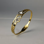 SVORA gold-plated stainless steel bracelet with black onyx and white mother-of-pearl clover charms and leaf detailing.