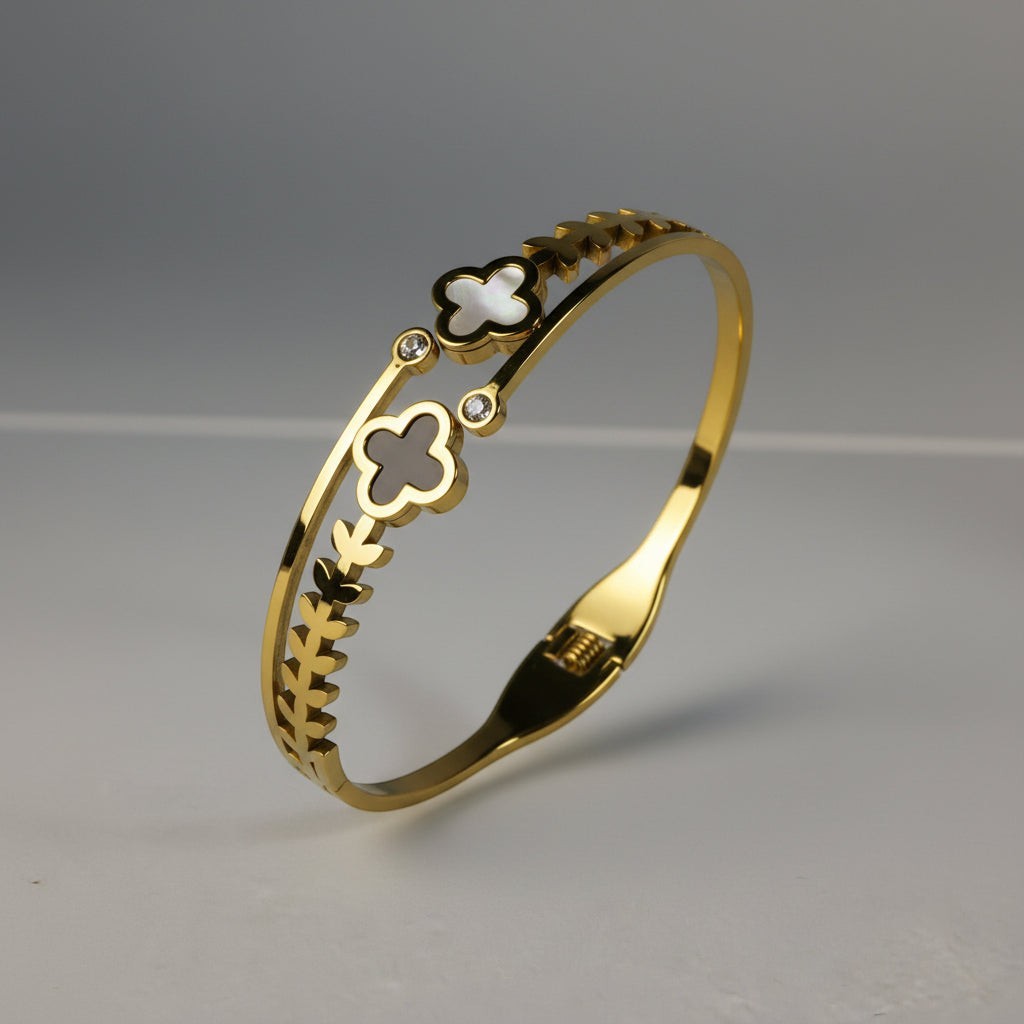 SVORA gold-plated stainless steel bracelet with black onyx and white mother-of-pearl clover charms and leaf detailing.