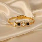 SVORA gold-plated stainless steel bracelet with alternating white mother-of-pearl clover and black onyx square motifs.
