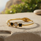 SVORA gold-plated stainless steel bracelet with alternating white mother-of-pearl clover and black onyx square motifs.